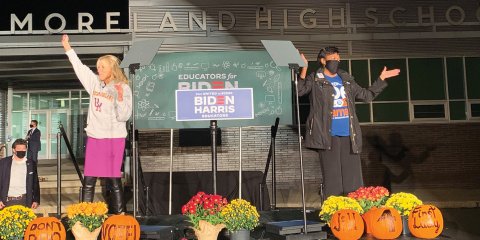 Jill Biden and NEA President Becky Pringle on a stage together with a Biden-Harris campaign sign behind them.